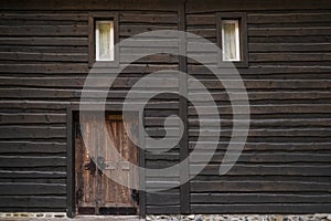 Wall of dark wooden beams , small windows and vintage door