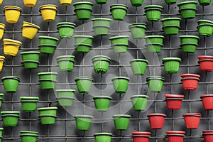 Wall decoration from grid with green, red and yellow flower pots on concrete wall. Modern city background, texture