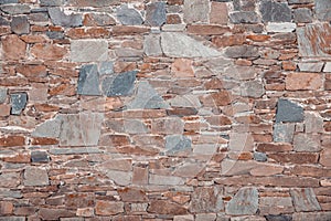 The wall of different colored natural stones forms a mosaic and a background