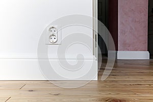 Wall with double rosette, white skirting board, solid wood parquet and column