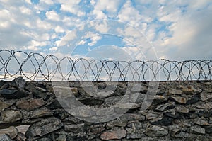 A wall of grey stone topped with barbed wire.