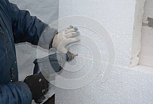Wall Insulation. Builder drilling wall for installing anchors to hold rigid insulation foam board.