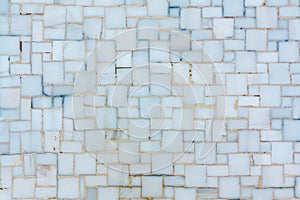 Wall lined with small bright ceramic or marble tiles, texture