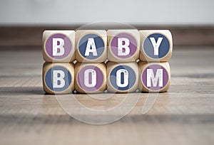 Wall made of cubes and dice with word baby boom on wooden background