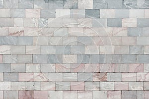 The wall is made of marble gray and pale pink tiles. Beautiful stone texture. Empty background.