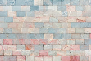 The wall is made of marble pink and pale blue tiles. Beautiful stone texture. Empty background.