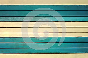 The wall is made of pale yellow and turquoise horizontal slats. Texture of thin painted boards.