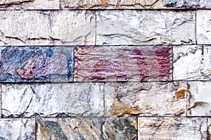 The wall is made of textured marble of different colors.