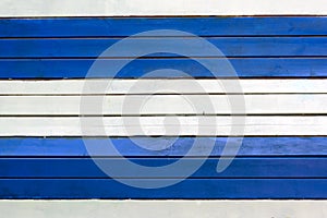 The wall is made of white and blue horizontal slats. Texture of thin painted boards.