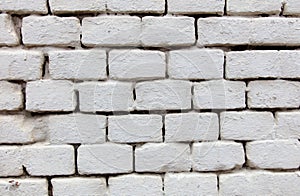 A white brick wall with a few bricks missing