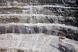 Wall of a modern diamond mine featuring big yellow machinery