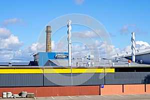 Wall of modern factory building and roof with exhaust and ventilation chimneys