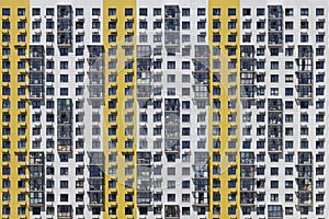 The wall of a new high-rise building in white and yellow with the same type of windows and balconies
