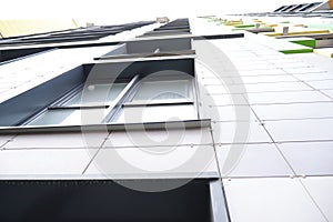 wall of office building made of metal plates with windows. Detail of modern residential building windows on ceramic