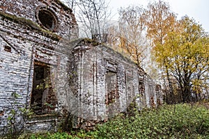 The wall of an old abandoned church among autumn yellow trees
