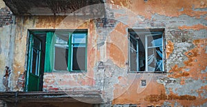 Wall of a house with peeling stucco and broken windows