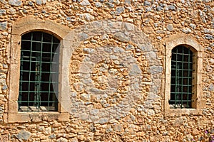 The wall of an old house with two windows.