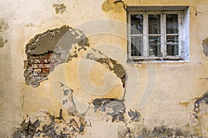 The wall of an old house with a window. The wall needs repair, Collapsed plaster and brickwork.
