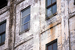 Wall of the old industrial building with windows and shabby pain