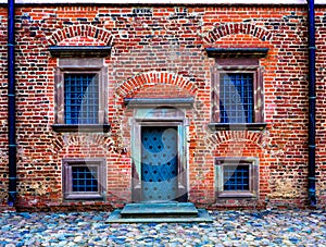 wall of the old red brick with dark door and symmetrical windows