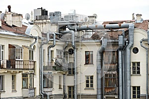 The wall of an old residential building in the city with large pipes of the cabling and conditioning system from the cafe