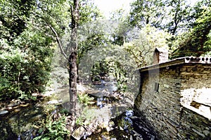 Wall of an old rural stone house next to a mountain river with l