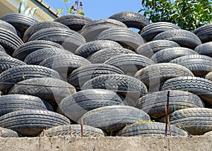 Wall of old tires. Unusual decoration of the land. Wheel fence. Penetration protection