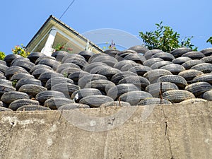 Wall of old tires. Unusual decoration of the land. Wheel fence. Penetration protection. Flowerbeds