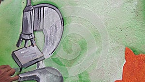 Wall painter draws a microscope on concrete wall.