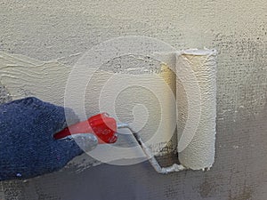 Wall painting with a roller. White-yellow paint