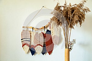 Wall panel in Boho style made of cotton beige, blue and red cords using macrame technique