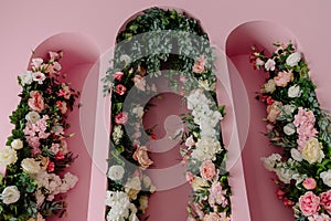 The wall is pink in the form of arches, decorated and decorated with a variety of flowers, artificial flowers.Modern