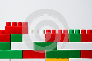 Wall from plastic building blocks isolated on a white background. Background from multi-colored details of a children`s