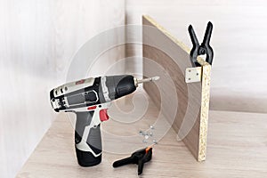 Wall plug dowel with screw, electric power drill, folding rule and pencil on wooden table - home improvement, repair or diy
