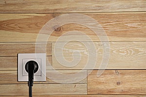 Wall with power socket and inserted plug, space for text. Electrical supply