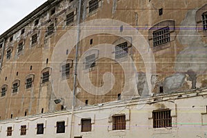 Wall of prison building with windows of pricon cells with bars