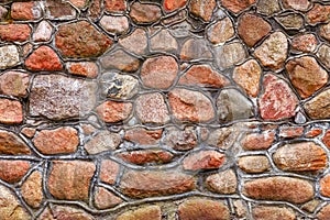 Wall of red granite cobblestones bonded with cement mortar