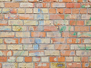 A wall of red and yellow bricks, stained with colored paints.