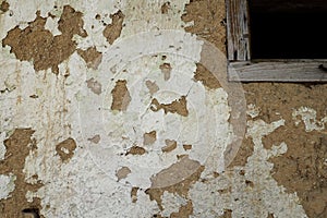 The wall of a residential old house built with bricks made from mud, cow dung and straw. Peeling plaster. Serbia