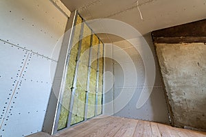 Wall of a room under renovation with mineral rock wool insulation and metal frame prepared for drywall plates