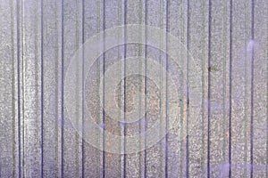 Wall of sheet metal. Blank background with colored lilac overflows. Texture of corrugated metal.