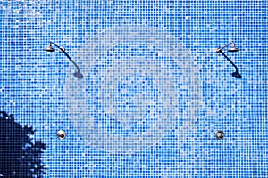 Wall of the showers of a swimming pool, in mosaic of blue tiles in the sun, without bathtubs due to the prohibition by coronavirus