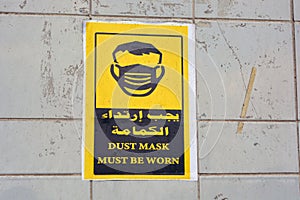Wall sticker in Arabic and English informs that face masks must be worn, the translation of Arabic words face mask is a must