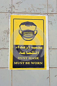 Wall sticker in Arabic and English informs that face masks must be worn, the translation of Arabic words face mask is a must