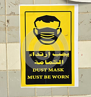 Wall sticker in Arabic and English informs that face masks must be worn, the translation of Arabic words face mask is a must