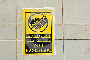 Wall sticker in Arabic and English , translation of Arabic words Avoid hand shake to prevent infection spread ,