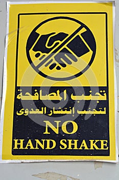 Wall sticker in Arabic and English , translation of Arabic words Avoid hand shake to prevent infection spread ,