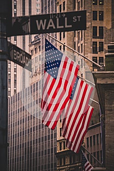 Wall street sign in New York with American flags and New York Stock Exchange in background