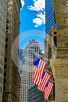 Wall Street, the sun illuminates the 3 American flags attached to the facade of the New York Financial district, Manhattan, New