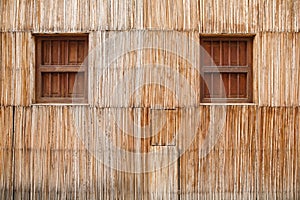 Wall of a thatched house with windows